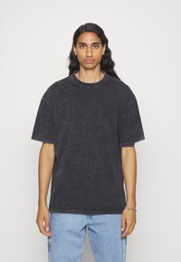 Sort oversized t-shirt med rund hals, korte ærmer og falmet tekstur. Pairer med lyseblå denim jeans.