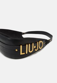 Schwarze Leder-Bauchtasche mit geschwungenem Design, die hervorgehobene goldene "LIU·JO"-Buchstaben und eine glatte Textur aufweist. Metallakzente enthalten.