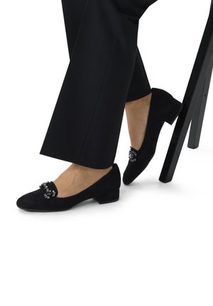 Zwarte suède schoenen met een laag hakje, voorzien van een decoratieve versiering op de bovenkant, met een ronde neus en een zachte textuur.