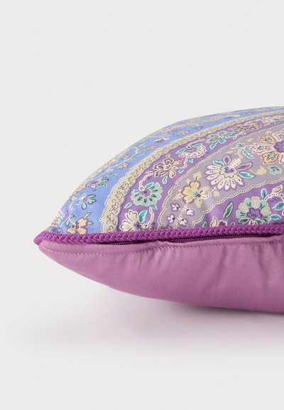 Coussin décoratif rectangulaire avec motif floral paisley violet et bleu et dos uni violet, bordé d'une bordure tressée violette.