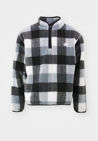 Svart och grå rutigt fleece-pullöver med hög krage, halv dragkedja framtill och subtil Nike-logotyp på vänster bröst. Mjuk, strukturerad tyg.