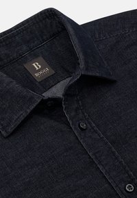 Camicia in denim scuro con colletto strutturato, bottoni neri e un'etichetta che recita "B Boggi Milano". Il tessuto presenta una sottile texture a coste.