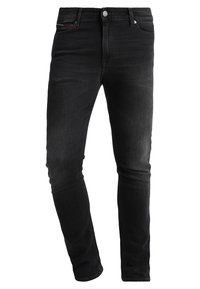 Jeans de mezclilla negra con un ajuste entallado. Presentan un diseño estándar de cinco bolsillos, cierre con botón de metal y áreas sutilmente descoloridas.