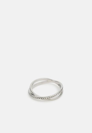 Bague en argent avec deux anneaux entrelacés, l'un uni et l'autre serti de petites pierres précieuses transparentes, sur un fond blanc uni.