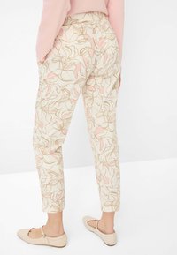 Pantalons légers de couleur crème ornés d'un motif floral en rose et or. Coupe crop, avec deux poches latérales et une coupe décontractée.