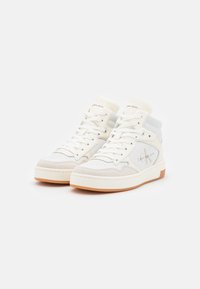 Białe skórzane sneakersy typu high-top z szarymi akcentami i beżowym zamszowym noskiem. Posiadają sznurowany design oraz gumową podeszwę. Widoczny logo Calvin Klein.