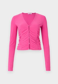 Long-sleeve, fitted pink top with a deep V-neck, ruched detailing down the front, and silver button accents for closure. Smooth texture.