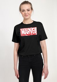 Černé bavlněné tričko s velkým, tučným, červenobílým grafickým logem "MARVEL" na přední straně. Standardní střih s krátkými rukávy.
