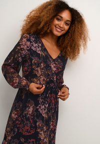 Long-sleeve floral dress in dark fabric featuring a V-neck, gathered waist, and colorful flower patterns in red, pink, and purple shades.