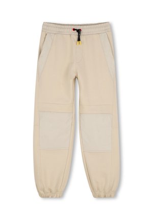 Pantalon de jogging beige avec ceinture et poignets élastiques, cordon noir et rouge, renforts beige clair aux genoux et poches latérales.