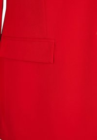 Roter Blazer mit strukturiertem Design, glattem Stoff, einer Aufgesetzte Tasche und klaren Linien, der seine lebendige Farbe und den taillierten Look betont.