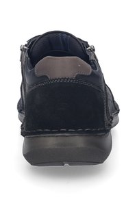 Zapato negro de cuero y ante con una superficie texturizada, cremallera trasera y acentos en gris contrastante; punta redondeada y suela acolchada.