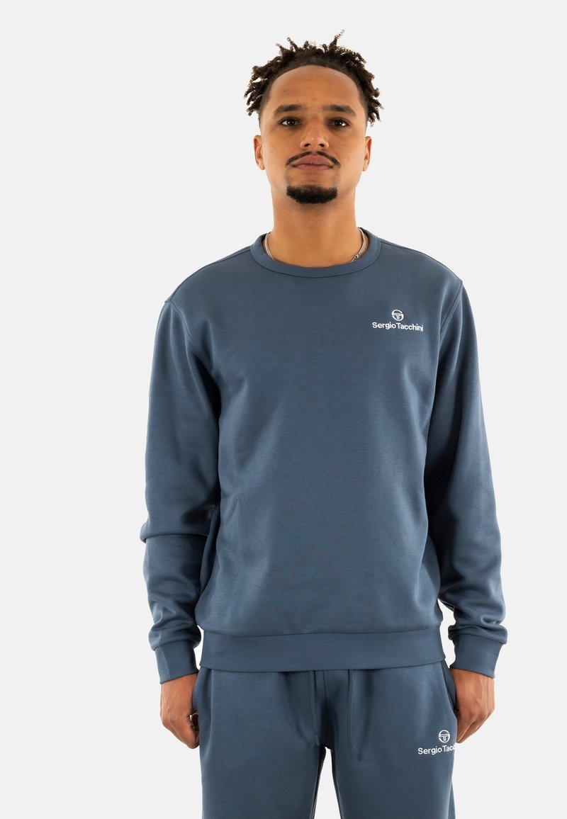 Sudadera de algodón azul con cuello redondo acanalado y mangas largas, que presenta el logotipo "Sergio Tacchini" bordado en el pecho.