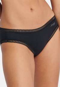 Sort bomulds-boksershorts med en bølget blondekant langs linningen. Designet er enkelt med glatte kanter og en behagelig pasform.