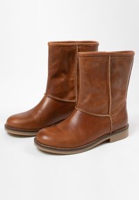 Bruine leren enkellaarzen met een gladde afwerking, ronde neus, minimale stiksels en een lage blokhak. Tijdloos en veelzijdig ontwerp.