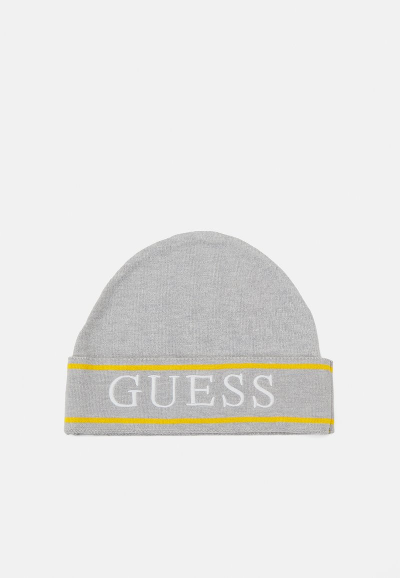 Grå strikket lue med rund topp og brett, prydet med en hvit "GUESS" logo, og med en gul stripe som detalj.