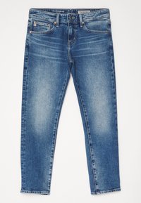 Modré slim-fit džíny s vybledlými efekty, předním knoflíkem a designem s pěti kapsami, položené na bílé ploše.