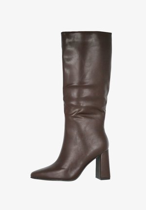 Botín de piel marrón oscuro hasta la mitad de la pantorrilla con punta afilada y tacón alto cuadrado, sobre un fondo blanco.