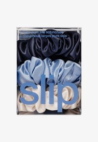 Drei große reine Seidenscrunchies in Marineblau, Hellblau und Creme, präsentiert in einer durchsichtigen Box mit blauem Textetikett. Weiche, glatte Textur.