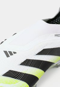 White and neon yellow soccer cleat with black stripes and textured surface, featuring a sock-like ankle collar and studded sole.