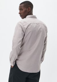 Cămașă gri deschis cu nasturi, cu mâneci lungi, textură moale, rever standard și slituri laterale. Partea din spate are un yoke simplu și detalii cusute.