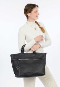 Sac fourre-tout en cuir noir avec surface texturée, poignées supérieures, poche zippée à l'avant et accents en métal argenté. Design simple et structuré.
