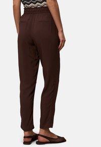 Hnědé lehké kalhoty s elastickým páskem a dvěma zadními kapsami, s designem rovného střihu a hladkou texturou látky.