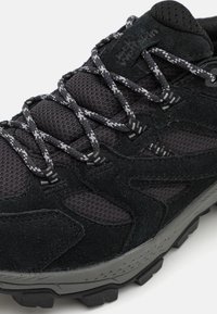 Black hiking shoe featuring a textured suede and mesh upper, reinforced laces, and a rugged rubber sole with traction patterns.