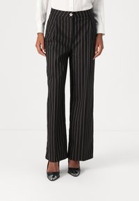 Black wide-leg trousers with orange vertical stripes, featuring a high waistband and a decorative silver accent at the front.
