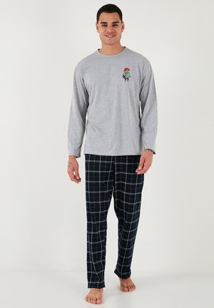 Cămașă gri cu mâneci lungi, cu un grafic colorat de desene animate pe piept, asortată cu pantaloni de pijama în carouri bleumarin. Material din amestec de bumbac.