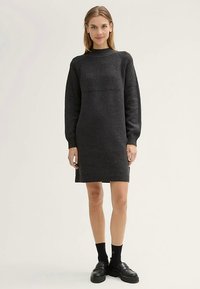 Ciemnoszara dzianinowa sukienka o prążkowanej fakturze, z długimi rękawami i wysokim kołnierzem. Posiada dopasowany krój i długość do połowy uda.