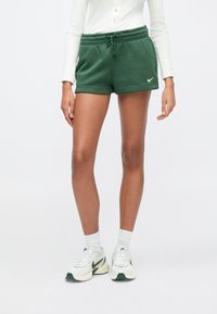 Πράσινα βαμβακερά σορτς με ελαστική μέση και κορδόνι, καθώς και πλαϊνές τσέπες, με μικρό λευκό λογότυπο Nike στο κάτω αριστερό μέρος.
