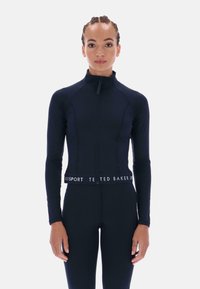 Námornícka modrá športová bunda so zipsom a dlhými rukávmi, s priliehavým strihom a elastickým pásom s logom. Hladká, elastická tkanina.