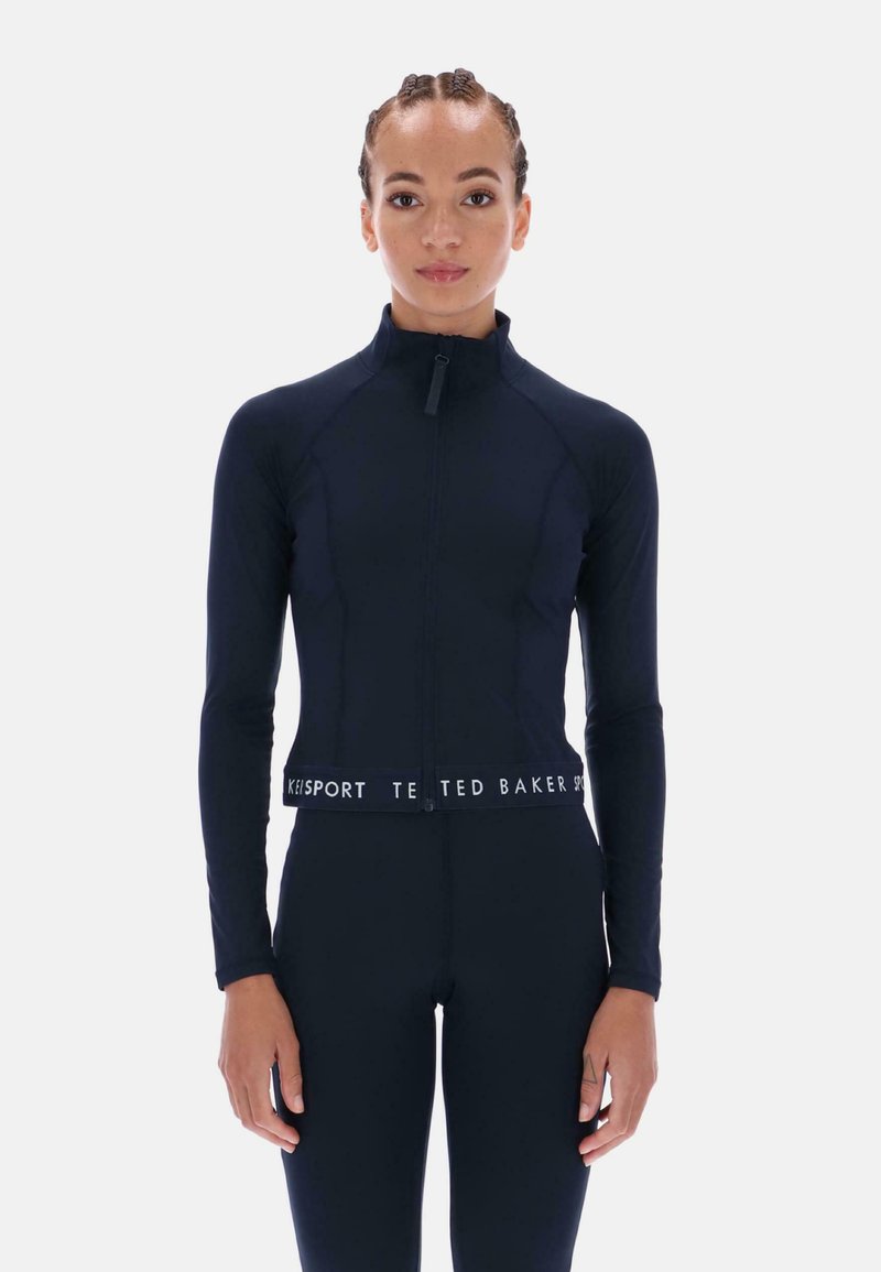 Námornícka modrá športová bunda so zipsom a dlhými rukávmi, s priliehavým strihom a elastickým pásom s logom. Hladká, elastická tkanina.