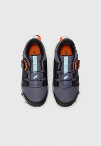 Lila und schwarze Sneakers aus Mesh-Stoff, mit verstellbarem Verschlussdial und orangefarbenen Akzenten. Verfügt über eine strukturierte Gummisohle und verstärkte Zehenpartie.