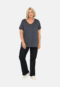 Donkergrijze v-hals t-shirt met korte mouwen, gecombineerd met donkere spijkerbroeken en witte sneakers, met een ontspannen pasvorm en een gladde textuur.