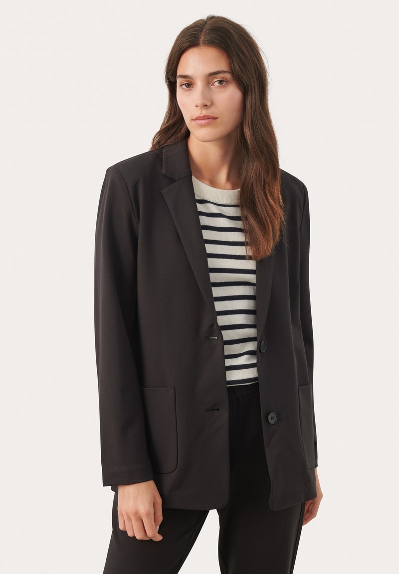 Zwarte blazer met een geklede revers, enkele-knoopsluiting, twee voorzakken en een gladde textuur, gelaagd over een gestreepte trui.