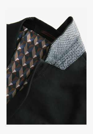 Svart jackkrage med geometriskt mönstrad foder i bruna, blå och beige nyanser. Tyg med textur och distinkta detaljer i kragens design.