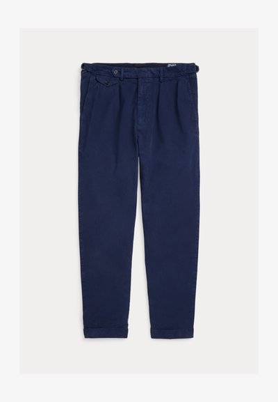 Ležerne hlače tamnoplave boje s naborima sprijeda, bočnim džepovima, kopčama za podešavanje struka i podvrnutim rubovima, položene ravno na svijetloj podlozi.