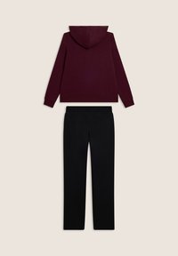 Felpa cappuccio bordeaux con tasca a marsupio e pantaloni neri con vita elastica, entrambi realizzati in morbido tessuto testurizzato.