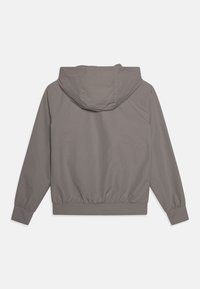 Grå hettejakke med elastisk nederkant og mansjetter, laget av glatt stoff og med en avslappet passform. Enkel, strømlinjeformet design uten pynt.