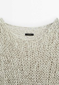 Crèmekleurige gebreide trui met een losse, open structuur, voorzien van een brede halslijn en een zwart etiket genaaid in de stof.