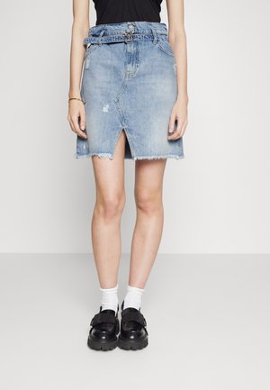 Gonna di jeans azzurra chiara con orlo sfilacciato, lunga fino al ginocchio, con uno spacco anteriore e una cintura abbinata. Indossata con scarpe nere e calze bianche.