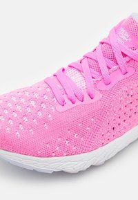 Pink athletic shoe with a breathable mesh upper featuring a textured surface, prominent laces, and a white rubber sole.
