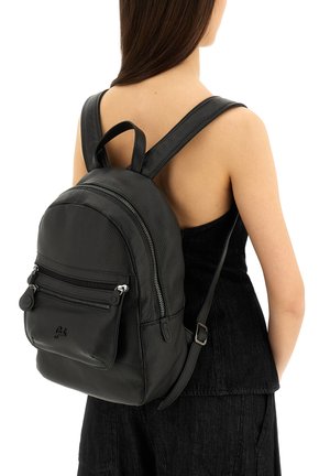 Zaino in pelle nera con finitura testurizzata, forma rotonda, doppie tasche frontali con zip, spallacci regolabili e un manico superiore come accentuazione.
