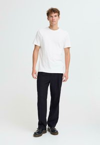 Witte T-shirt met korte mouwen, ontspannen pasvorm. Zwarte pinstripe broek, rechte pijpen. Zwarte veterschoenen maken de outfit compleet. Eenvoudig design, minimalistische accenten.