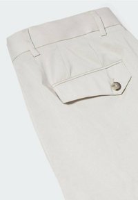 Pantalons en coton beige avec une texture lisse, dotés d'une poche arrière à bouton et d'un détail de taille cintrée.