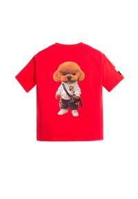 Camiseta de algodón roja con una impresión gráfica en la espalda de un perro esponjoso vestido con un traje de karate, pantalones negros y zapatillas blancas.