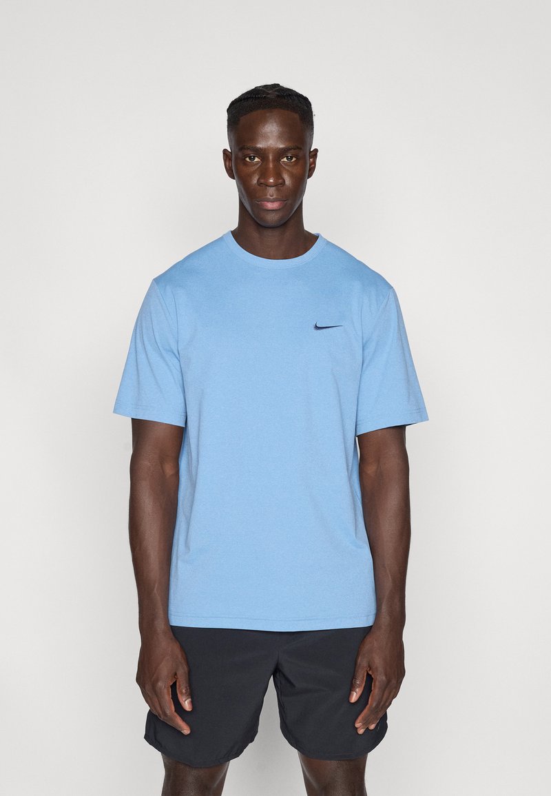 Φωτεινό γαλάζιο μπλουζάκι με στρογγυλή λαιμόκοψη από απαλό ύφασμα, με μικρό μαύρο λογότυπο Nike στο αριστερό στήθος, συνδυασμένο με μαύρο σορτς.