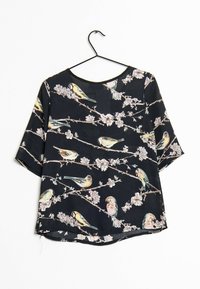 Blouse à manches courtes en tissu noir avec un imprimé floral et d'oiseaux. Encolure ronde et ourlet légèrement arrondi. Texture lisse, légère.
